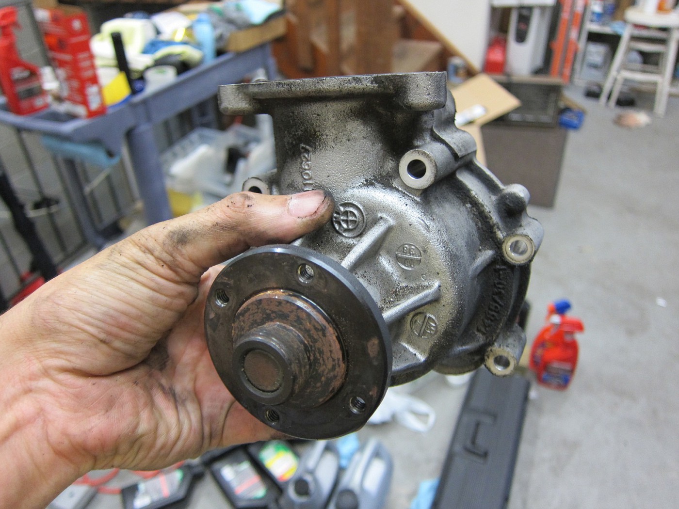 Mechanic holding a Nissan forklift water pump after being removed from the lift truck